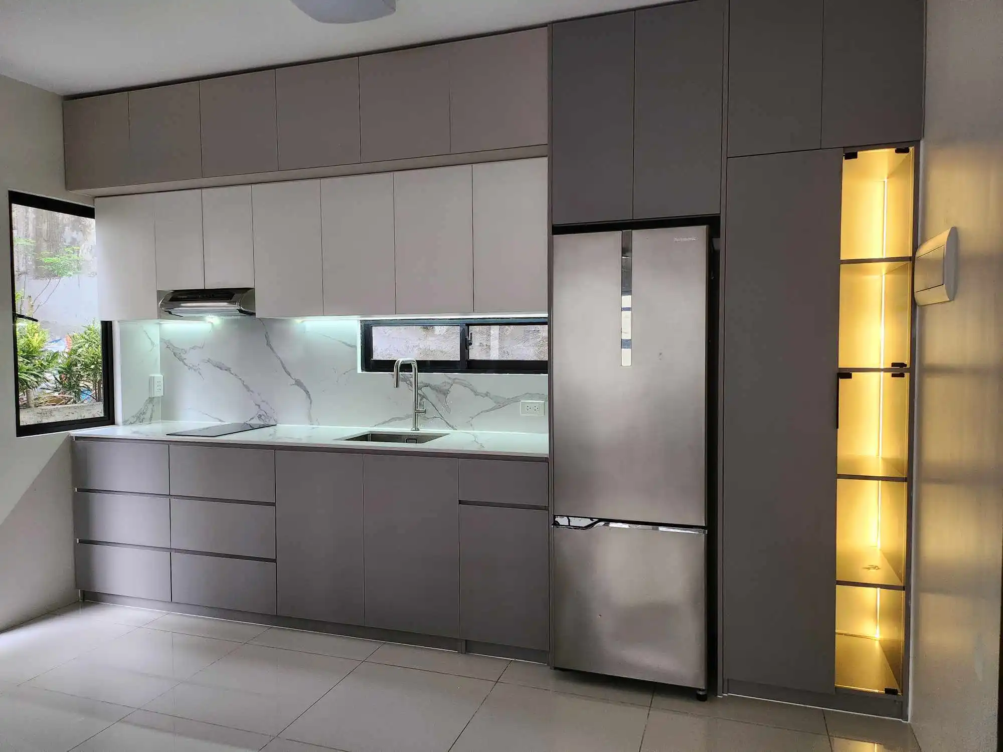 Modern gray modular kitchen with built-in cabinets and refrigerator