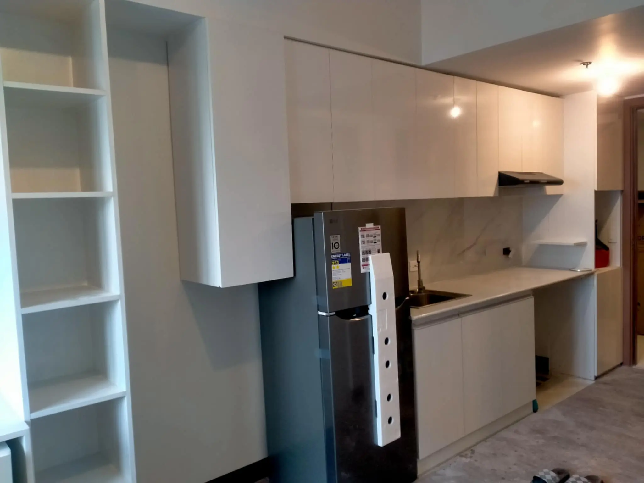 Modern white modular kitchen with built-in cabinets and refrigerator