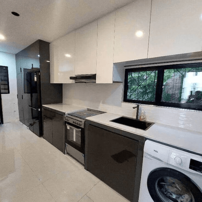 Custom modular kitchen cabinet with black and white finish, built-in appliances, and modern space-saving design.