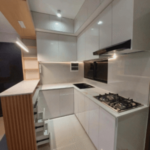Custom modular kitchen cabinet with glossy white finish, built-in cooktop, and modern space-saving design.